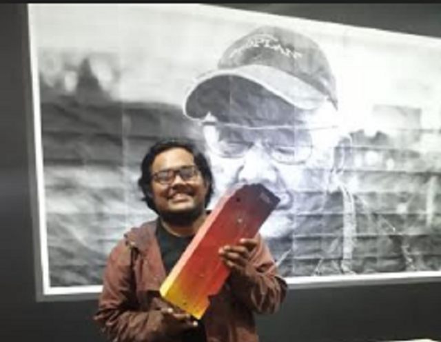 Vincent Rumahloin berpose dengan latar karyanya berajuk "Don't Call Me Hero: Soegeng Soejono". Karya ini jadi pemenang Bandung Contemporary Art Award (BaCAA) 2019. (Dok Istimewa)