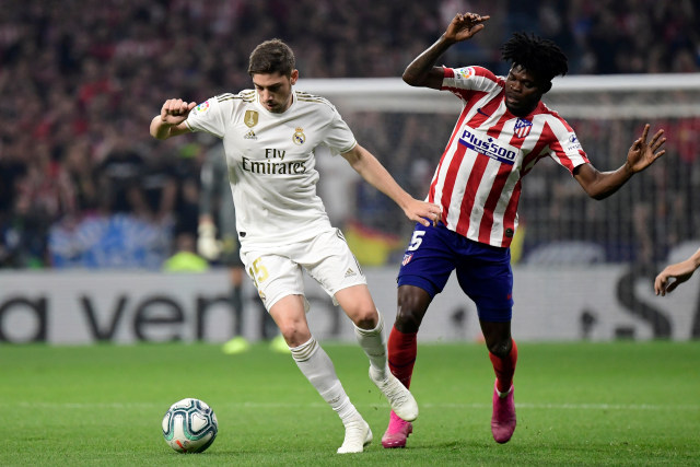 Pemain Real Madrid, Federico Valverde (kostum putih-putih),  saat merebut bola dari pemain Atletico Madrid, Thomas Partey. Foto: AFP/JAVIER SORIANO