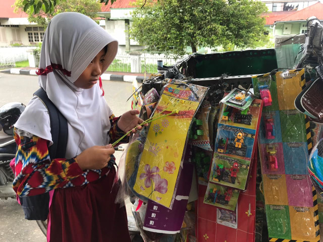 Seorang anak sedang mencari mainan yang dijual Mamang Seribu di Pontianak. Foto: Teri/Hi!Pontianak
