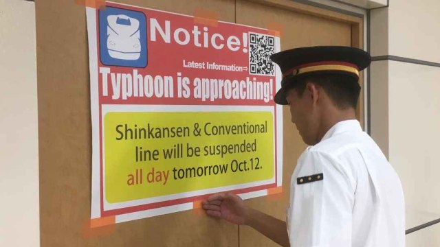 Seorang anggota staf kereta api Kakegawa menempelkan poster yang bertuliskan " Topan mendekat" ke dinding di stasiun, Stasiun Kakegawa, Jepang .  Foto: REUTERS
