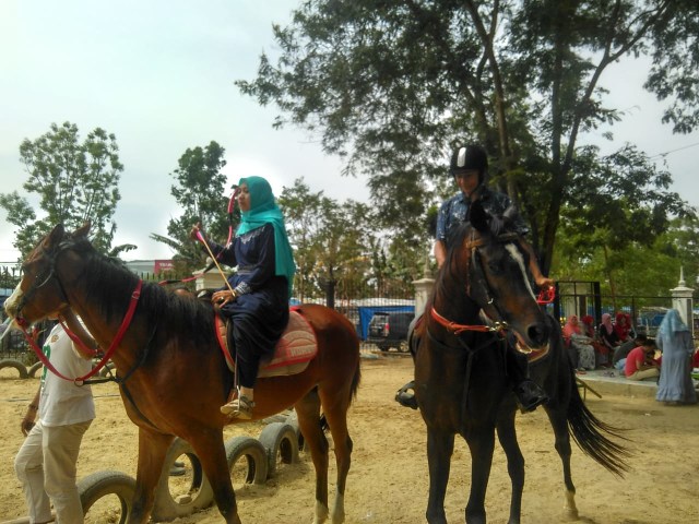 Seorang ibu sedang menunggang kuda sembari memegang busur panah, Minggu (13/10) | Foto : Sidik Aryono/Lampung Geh