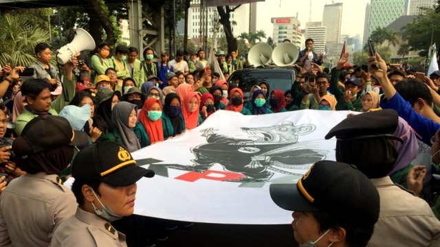 Mahasiswi menyerahkan spnduk bergambar tikus dengan tulisan KPK kepada polwan.
 Foto: Andesta Herli Wijaya/kumparan