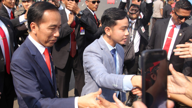 Presiden Joko Widodo (kiri) didampingi putranya Gibran Rakabuming (kanan) menyalami warga di depan Istana Negara, Jakarta, Minggu (20/10).  Foto: ANTARA FOTO/Rachman
