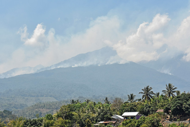 Asap kebakaran di kawasan hutan Pelawangan Senaru Gunung Rinjani membubung ke udara terlihat dari Desa Senaru, Kecamatan Bayan, Lombok Utara, NTB, Senin (21/10) Foto: ANTARA FOTO/Ahmad Subaidi
