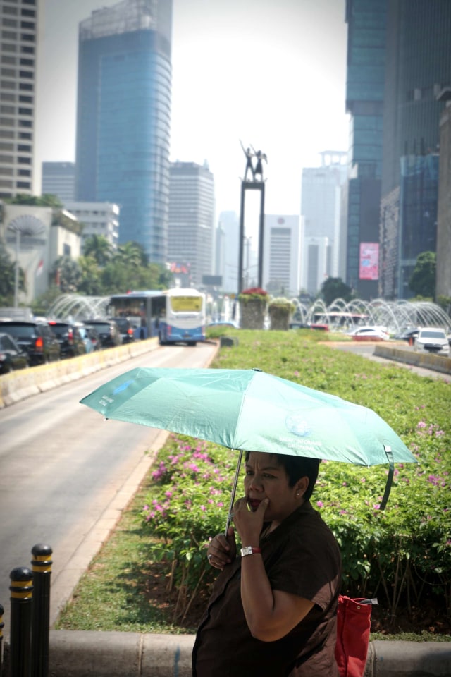 Seorang warga menggunakan payung guna terhindar dari panasnya matahari, Jakarta, pada Selasa (22/10/2019). Foto: Iqbal Firdaus/kumparan