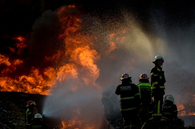 Petugas berusaha memadamkan api saat kebakaran pipa minyak milik PT Pertamina di Melong, Cimahi, Jawa Barat, Selasa (22/10/2019).  Foto: ANTARA FOTO/Raisan Al Farisi