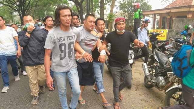 Pelaku (tengah, celana pendek) saat dibawa petugas kepolisian untuk menunjukkan tempat korban dikubur (foto: istimewa)