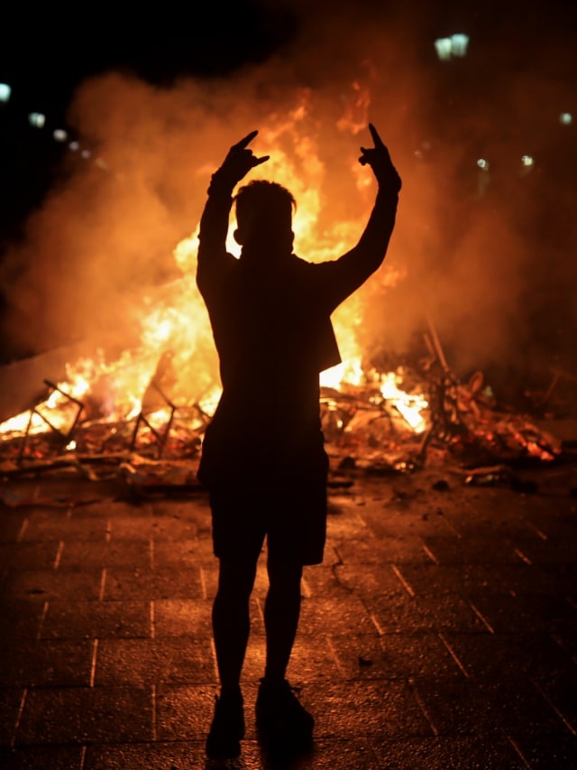 Seorang demonstran berdiri di depan kobaran api saat demo di Santiago, Chile, Senin (28/10/2019). Foto: REUTERS/Pablo Sanhueza