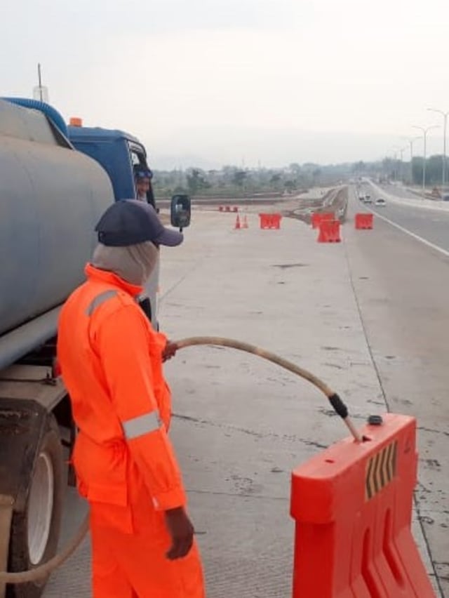 Petugas Jasa Marga mengisi air ke water barrier di Tol Pandaan Malang. Foto: Dok. Jasa Marga
