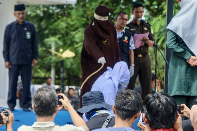 Algojo menghunus rotan saat mengeksekusi hukuman cambuk terhadap pelanggar syariat Islam yang dilaksanakan di Taman Bustanussalatin, Banda Aceh, Kamis (31/10). Foto: Suparta/acehkini