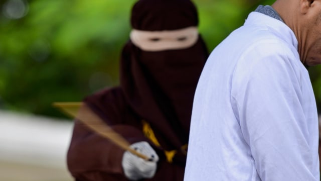 Ilustrasi hukum cambuk. Foto: AFP/CHAIDEER MAHYUDDIN