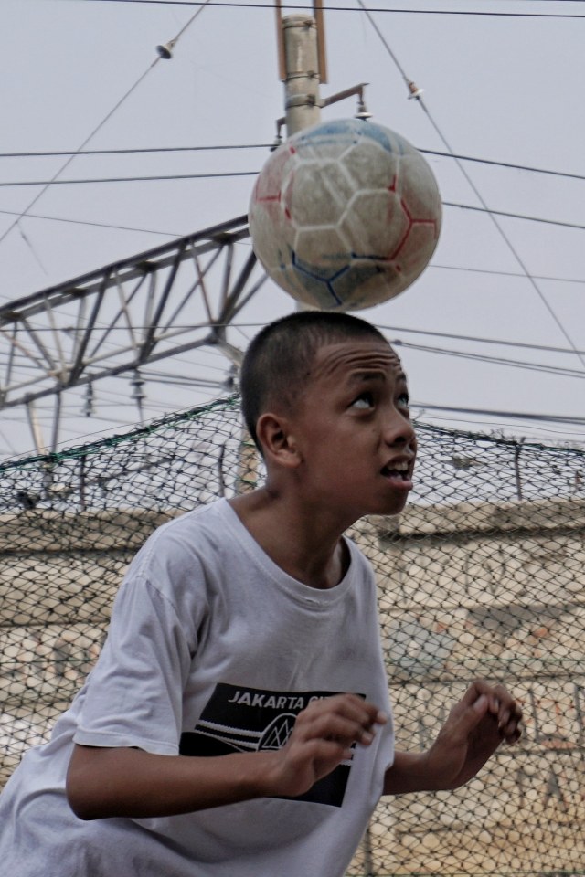 Seorang anak menyundul bola saat bermain bola di pinggir rel kereta di kawasan Kalianyar, Tambora, Jakarta Barat, Selasa (5/11/2019). Foto: Jamal Ramadhan/kumparan