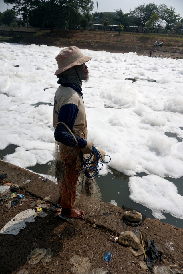 Salah satu warga mencari ikan di area limbah busa yang muncul di Pintu Air KBT di Ujung Menteng, Jakarta Timur, Kamis (7/11). Foto: Iqbal Firdaus/kumparan