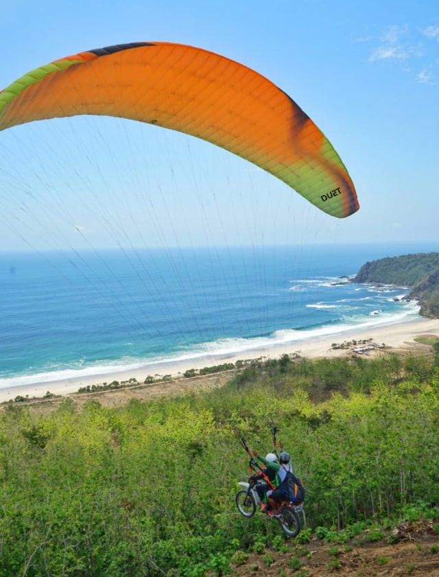 Pesepeda motor terbang dengan paralayang di Pantai Modangan, Kabupaten Malang. Foto: doli siregar/mboislife magazine for tugumalangid