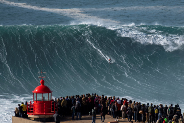 Peselancar asal Brazil Rodrigo Koxa meluncur di atas ombak di Nazare. Foto: AFP/Olivier MORIN