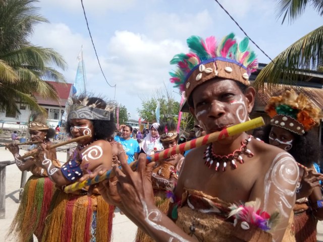 Permpuan di Raja Ampat sedang meniup suling, foto: Aditya Nugroho