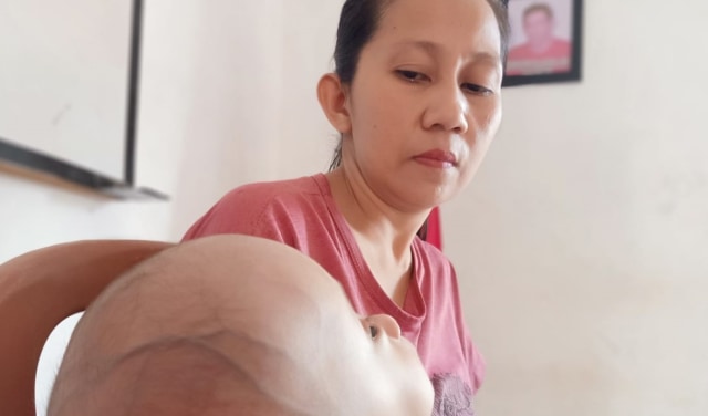 Saadia Suleman Aziz (37), ibu kandung bayi bernama Putra yang mengidap hidrosefalus saat merawat sibuah hatinya. Foto: Moh. Sabran/PaluPoso
