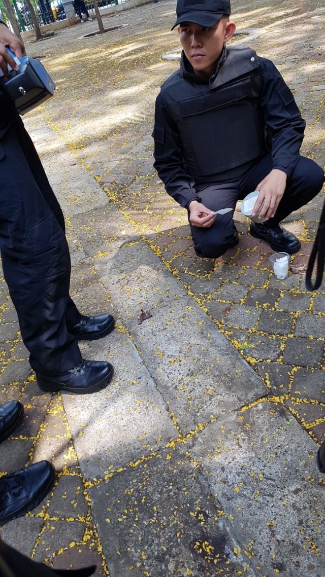 Petugas memeriksa kaca yang diduga serpihan dari jam tangan di sekitar lokasi ledakan di Monas. Foto: Efira Tamara Thenu/kumparan