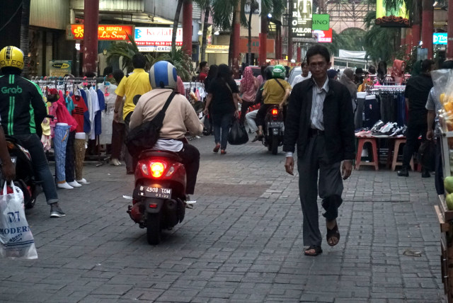 Pengendara motor melintas di samping pedagang di Pasar Baru, Jakarta, Selasa (3/12).  Foto: Iqbal Firdaus/kumparan 