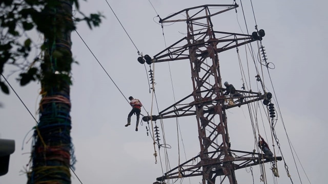 Petugas PLN memperbaiki menara sutet miring di Jalan Arif Rahman Hakim, Beji, Depok, Jumat (6/12).
 Foto: Irfan Adi Saputra/kumparan