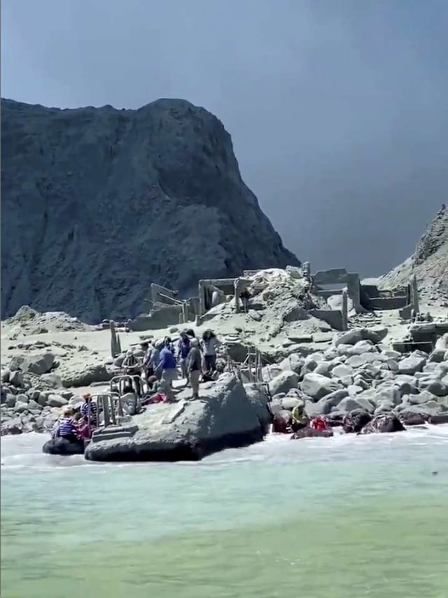 Orang-orang menunggu untuk dievakuasi di tengah asap dari letusan gunung berapi Whakaari, juga dikenal sebagai Pulau Putih, di Selandia Baru, Senin (9/12). Foto: @SCH/via REUTERS