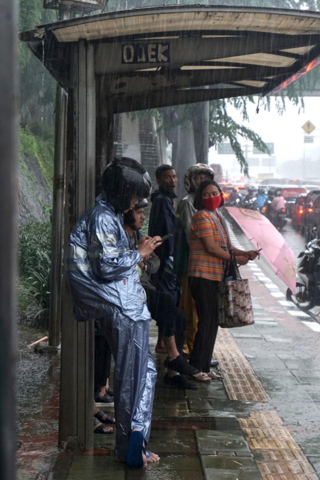 Sejumlah pengendara motor berteduh di halte bus, di kawasan Gatot Subroto, Jakarta Selatan, Selasa (17/12). Foto: Iqbal Firdaus/kumparan