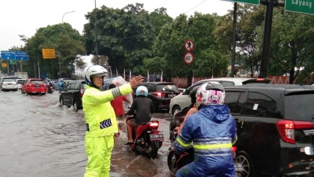 Polisi mengatur lalu lintas di tengah jalanan yang terendam. Foto: Twitter/ @TMCPoldaMetro