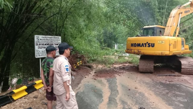 Petugas sedang membersihkan material longsor yang memutus jalan raya Soreang-Ciwidey, Kabupaten Bandung, Selasa (17/12). (Foto: Istimewa)