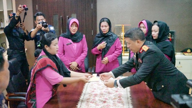 KAPOLDA Riau, Irjen Pol Agung Setya Imam Effendi menyerahkan secara simbolis kunci rumah kepada istri almarhum Bripka Anumerta Hendra Saut Parulian Sibarani, Hotmaida Boru Sinagar, Minggu, 22 Desember 2019, di Mapolda Riau. 