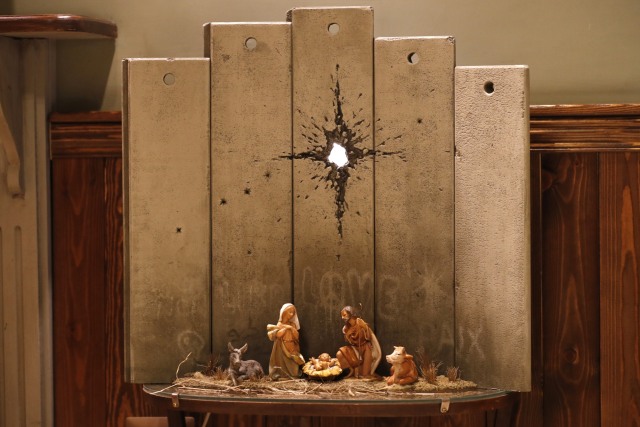 Sebuah karya seni bertema Natal yang dijuluki "Scar of Betlehem" oleh seniman Inggris Banksy yang terpajang ditampilkan di Walled-Off Hotel di Bethlehem.  Foto: AFP/AHMAD GHARABLI