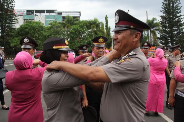 Sepasang suami istri yang saling memasangkan pangkat saat korps raport kenaikan pangkat di Halaman Mapolresta Bandar Lampung, Selasa (31/12) | Foto: Obbie Fernando/Lampung Geh