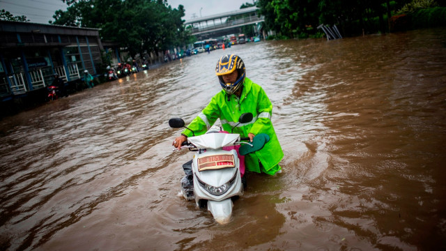 Warga mendorong motornya melintasi genangan banjir di Jalan DI Panjaitan, Cawang, Rabu (1/1/2020). Foto: ANTARA FOTO/Aprillio Akbar