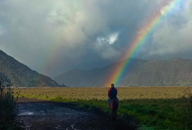 Seorang pengendara kuda menikmati keindahan pelangi di Gunung Bromo pada Minggu (5/1/2020) pagi kemarin. (Foto: Tanah Alas Indonesia)