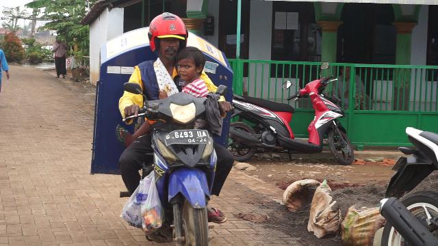 Tarmuji, jualan roti keliling sambil menggendong anaknya yang lumpuh. (Foto: Syaifullah)