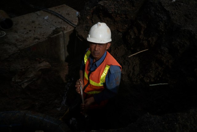 Petugas saat memperbaiki pipa PDAM di jalan yang amblas di Daan Mogot, Tangerang, Senin (14/1/2020). Foto: Jamal Ramadhan/kumparan