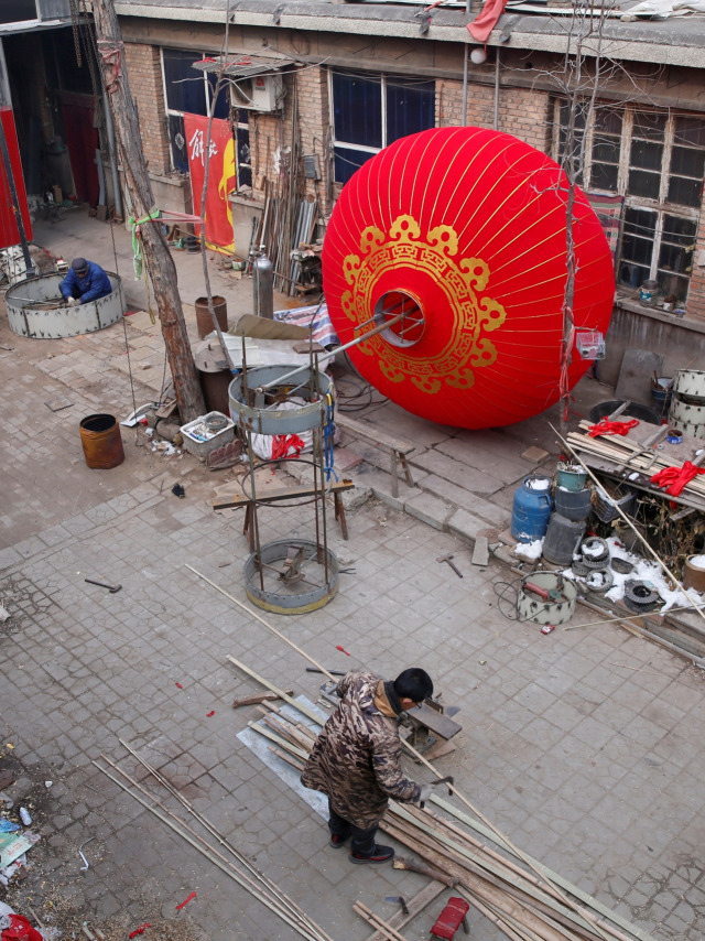 Penduduk lokal Bai Junping membuat lampion tradisional raksasa menjelang perayaan Tahun Baru Imlek Cina di desa Tuntoucun, di Shijiazhuang, China. Foto: REUTERS/Jason Lee