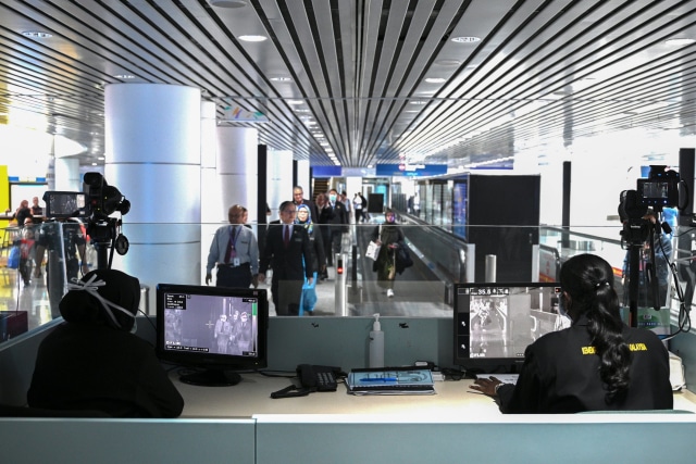 Petugas kesehatan Malaysia menggunakan 'thermal scanner' mendeteksi suhu tubuh penumpang yang tiba di Bandara Internasional Kuala Lumpur, Malaysia. Foto: AFP/MOHD RASFAN 