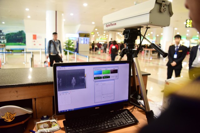 Petugas menggunakan 'thermal scanner' mendeteksi shuhu tubuh penumpang yang tiba di Bandara Internasional Noi Bai, Hanoi, Vietnam.  Foto: AFP/HOANG AN