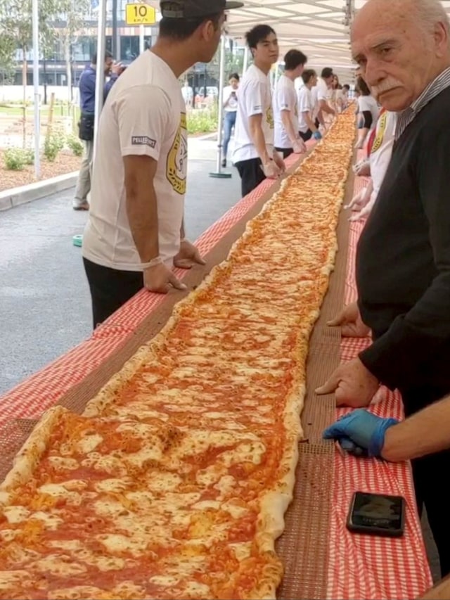Pizza sepanjang 100 m untuk membuat rekor baru untuk pizza terpanjang Australia dan mengumpulkan dana untuk Layanan Pemadam Kebakaran Pedesaan New South Wales. Foto: Instagram/@ISSAC_EATSALOT via REUTERS