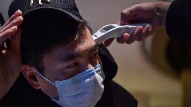 Petugas memindai masyarakat dengan alat khusus untuk mendeteksi virus corona di Wuhan, China. Foto: AFP/HECTOR RETAMAL