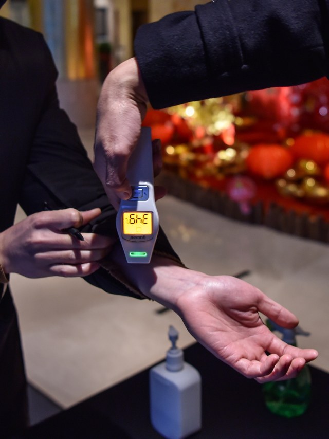 Petugas memindai masyarakat dengan alat khusus untuk mendeteksi virus corona di Wuhan, China. Foto: AFP/HECTOR RETAMAL