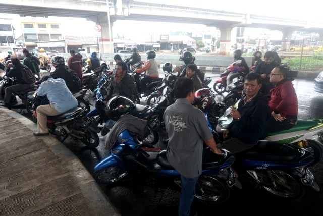 Pemotor berteduh di bawah jalan layang saat hujan deras. Foto: Iqbal Firdaus/kumparan