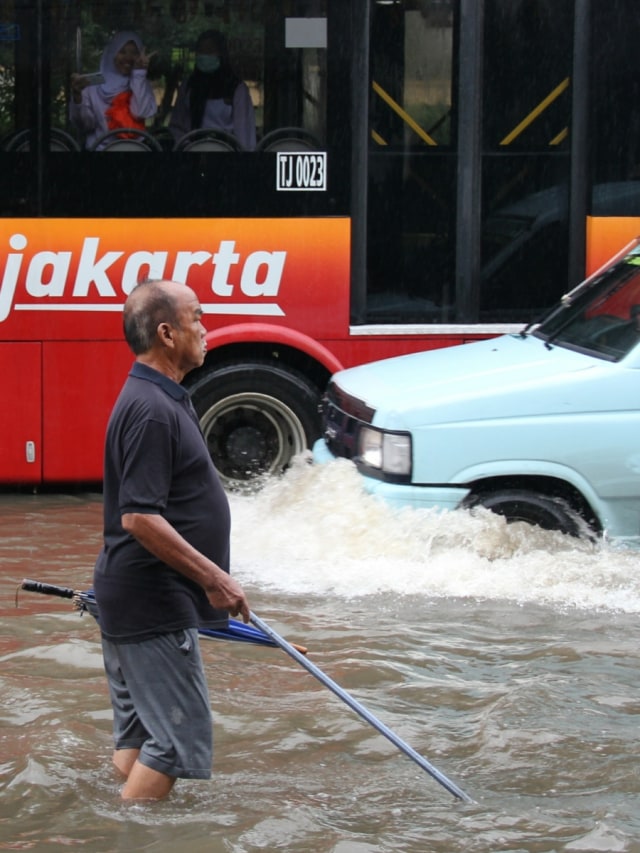 Seorang warga tuna netra berjalan saat banjir di Jalan Gunung Sahari, Jakarta Utara, Jumat (24/1). Foto: Nugroho Sejati/kumparan