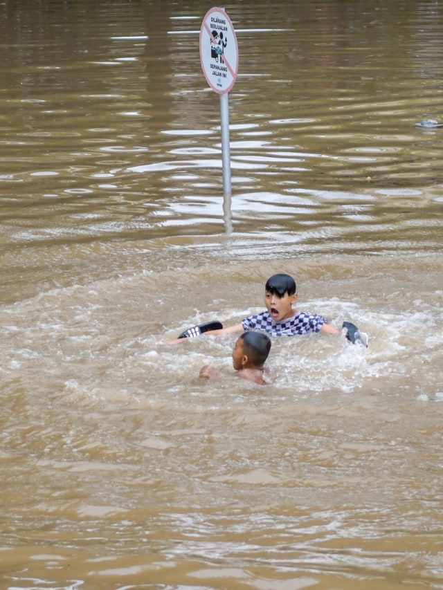 Sejumlah anak bermain saat banjir menutup terowongan di jalan Kota Baru Bandar Kemayoran, Jakarta, Jumat (24/1).  Foto: ANTARA FOTO/Galih Pradipta