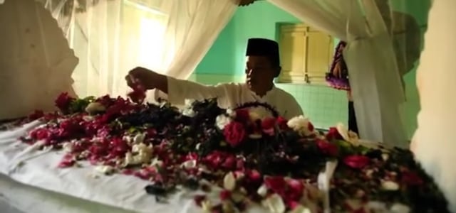 Seseorang sedang menaburkan bunga ke makam dalam tradisi Nyadran. Foto: Istimewa.