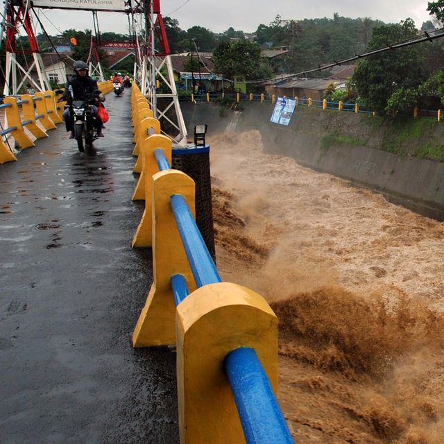 Pengendara motor melintas diatas jembatan saat tinggi muka air sungai Ciliwung naik di Bendung Katulampa, Kota Bogor, Jawa Barat, Rabu (1/1/2020). Foto: ANTARA FOTO/Arif Firmansyah
