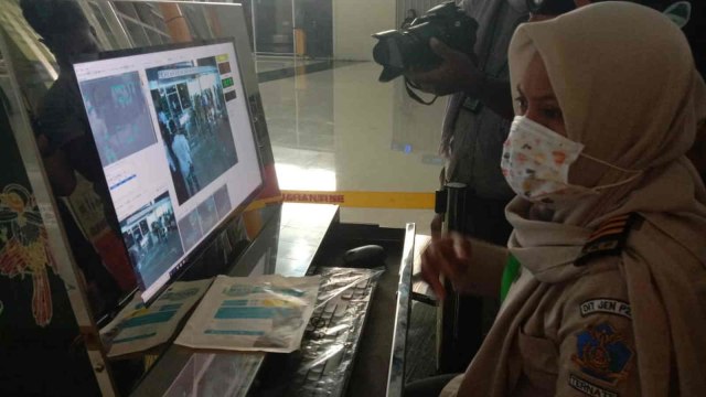 Seorang petugas kesehatan mengamati serius gerak gerik penumpang di terminal kedatangan Bandara Sultan Babullah Ternate, Maluku Utara. Foto: Nurkholis Lamaau/cermat