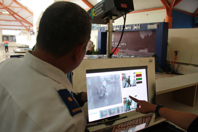 Petugas melakukan pengecekan suhu tubuh para penumpang melalui monitor thermal scanner. (Foto: Bayu Eka Novanta)
