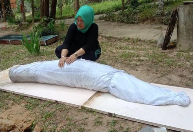 Netty Herawaty bersama ikan aripaima yang sudah dikafani (Foto: Ist)