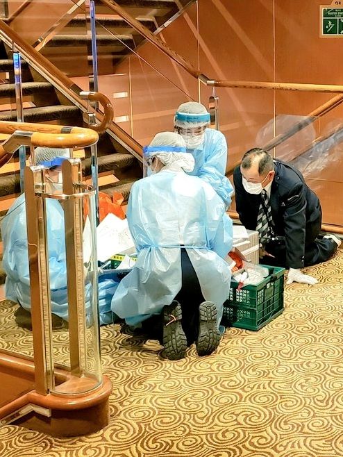 Petugas menggunakan pakaian pelindung berada di atas dek kapal pesiar Diamond Princess yang dikarantina di pelabuhan Yokohama, Jepang, Selasa (4/2). Foto: Twitter / @DAXA_TW via REUTERS